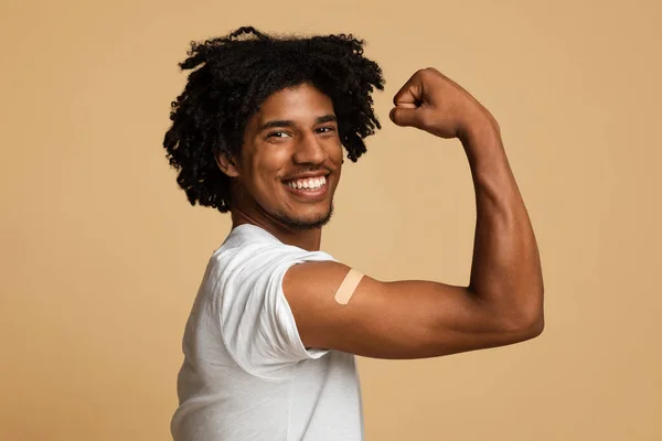 Emocionado hombre afroamericano mostrando brazo con yeso después de recibir la vacuna Covid-19 —  Fotos de Stock