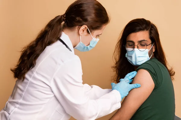 Vrouwelijke arts maakt intramusculaire injectie voor arabische man in kliniek — Stockfoto