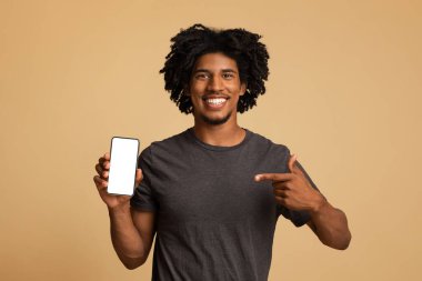 Neşeli siyah adam elinde beyaz perdesiyle akıllı telefonu işaret ediyor.