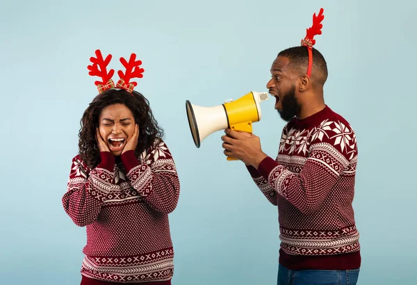 Hombre negro gritando con megáfono altavoz a la mujer, de pie juntos sobre fondo azul — Foto de Stock