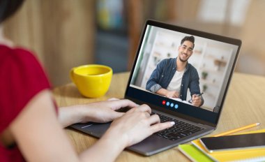 Gülümseyen genç Arap erkek öğrenci uzaktan öğreniyor, Avrupalı kadın öğretmenle dil öğreniyor.