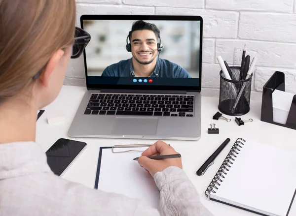 Concentrated millennial female study online, learn english and look at arabic guy on laptop screen — Stock Photo, Image