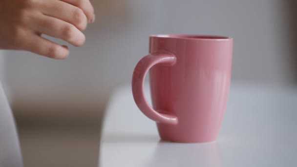 Hábitos saludables. Primer plano de joven irreconocible yacía tomando taza de color rosa con té caliente o café de la mesa, cámara lenta — Vídeos de Stock