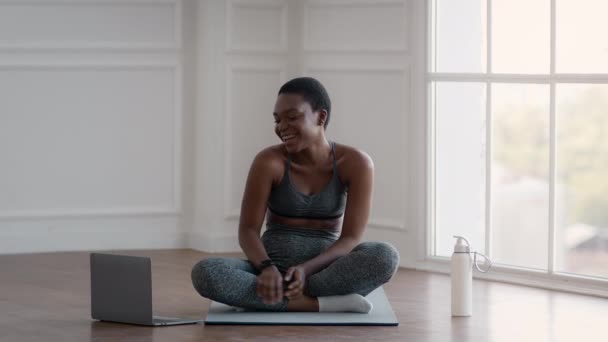 Веселая черная спортивная женщина с видеозвонком на ноутбук с тренером по фитнесу — стоковое видео