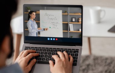 Arap milenyumu erkeği dizüstü bilgisayara bakar Avrupalı bayan öğretmene bakar, evde çalışır, uzaktan İngilizce öğrenir.