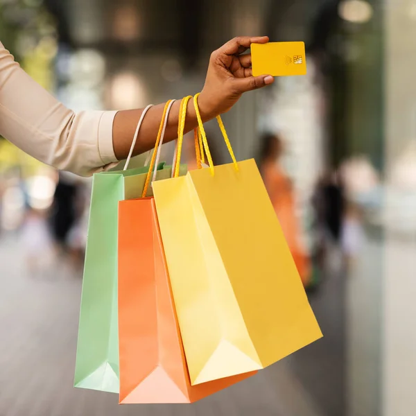 Consumidor negro irreconocible con tarjeta de crédito y bolsas de compras —  Fotos de Stock
