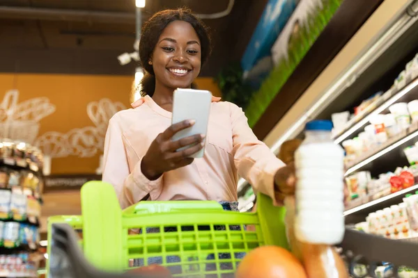 アフリカ系アメリカ人女性スーパーで電話で食料品の買い物をする — ストック写真