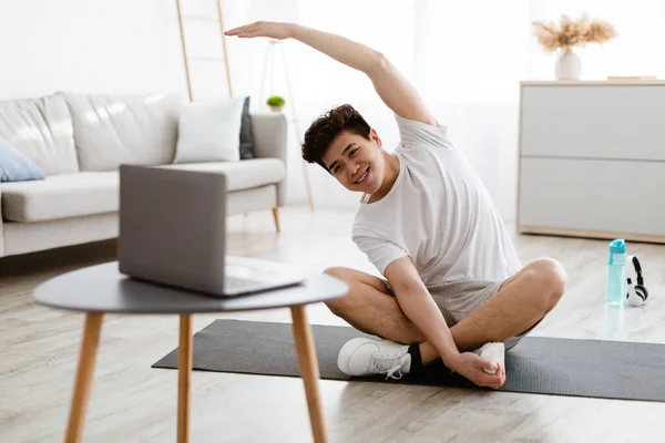 Ασιάτης τύπος κάνει διατάσεις άσκηση βλέποντας online φροντιστήριο — Φωτογραφία Αρχείου
