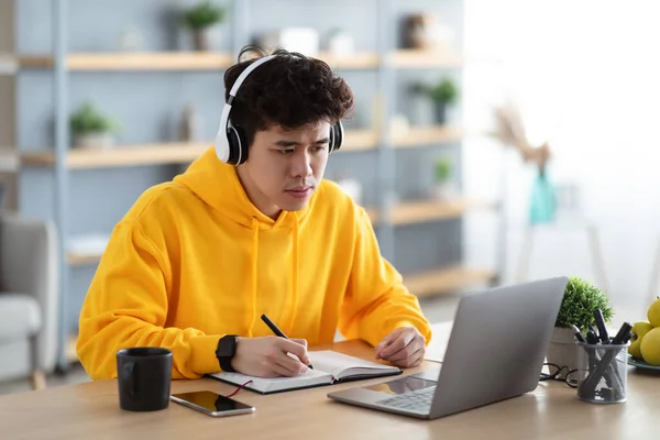 Focalizzato asiatico uomo lavorando su laptop e scrittura — Foto Stock