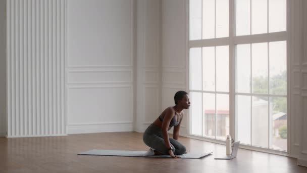 Yoga en línea. Deportiva mujer negra encendiendo la lección de video en el ordenador portátil y comenzar la práctica de meditación — Vídeos de Stock