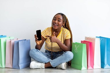 Duygusal siyahi kadın alışverişte cep telefonunu boş ekranla gösteriyor.