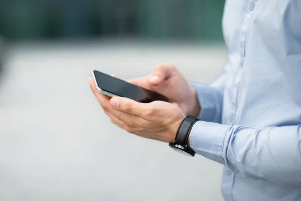 Hombre de negocios irreconocible sosteniendo un teléfono inteligente moderno con pantalla en blanco, maqueta — Foto de Stock