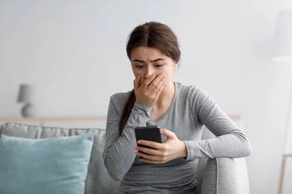 Chockad ledsen förtvivlade kaukasiska tusenåriga kvinna täcker hennes mun efter att ha läst dåliga nyheter i meddelandet på smartphone — Stockfoto