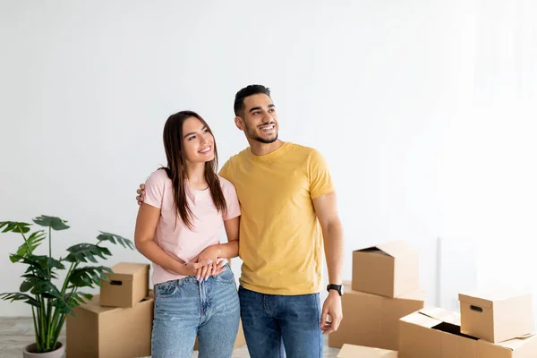 Feliz joven pareja multirracial de pie en su casa entre cajas de cartón en el día de la mudanza, espacio de copia —  Fotos de Stock