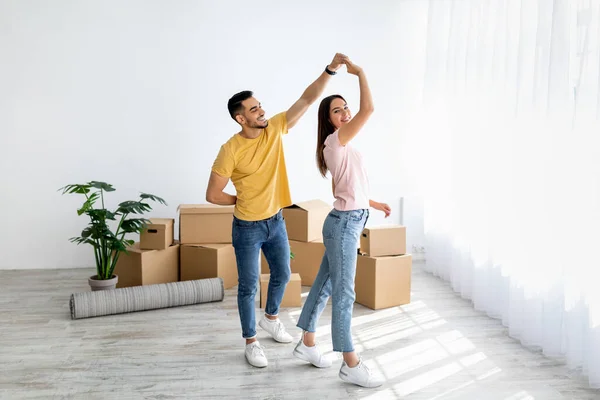 Casal multirracial afetuoso dançando em sua casa entre caixas de papelão no dia em movimento, espaço livre — Fotografia de Stock