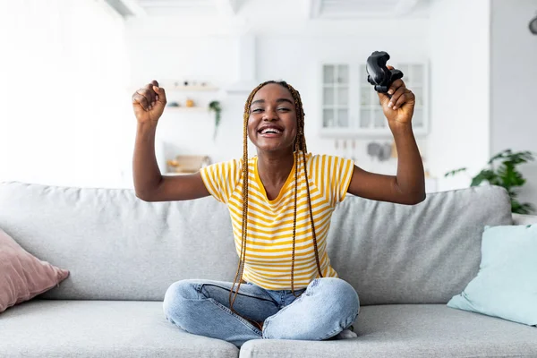 Emocional joven mujer negra ganadora jugando videojuegos en casa —  Fotos de Stock