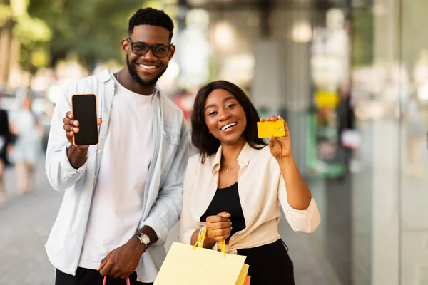 Portrét šťastného afro páru pomocí smartphonu držící kreditní kartu — Stock fotografie