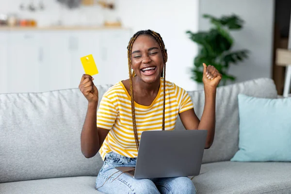 Mujer afro-americana emocional con tarjeta de crédito y portátil, espacio para copiar —  Fotos de Stock