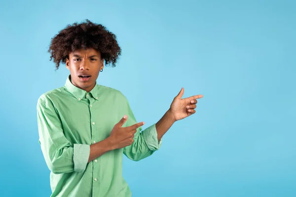 Émotionnel afro-américain adolescent gars pointant de côté à l'espace vide avec deux mains, fond bleu — Photo