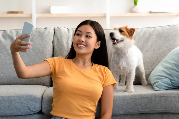Sonriendo joven asiático mujer tomando selfie con su lindo perro — Foto de Stock