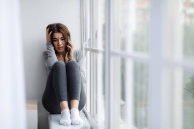 Ağlayan, depresyon ve iletişim problemleri yaşayan, telefonla konuşan, endişeli, beyaz bir kadın.