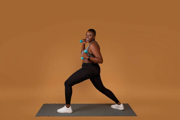 Paffuto nero esercizio con manubri su yoga mat — Foto Stock
