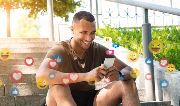 Sonriente joven afroamericano atleta masculino charlando por teléfono en las redes sociales, en las escaleras de la ciudad — Foto de Stock