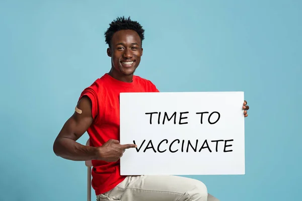 Veselý černoch drží plakát s časem na očkování motivační nápis — Stock fotografie