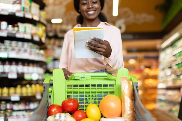 Africano americano senhora leitura mercearia lista de compras a pé no supermercado — Fotografia de Stock