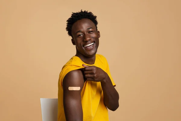 Allegro ragazzo nero mostrando braccio con gesso dopo successo Covid-19 vaccino girato — Foto Stock