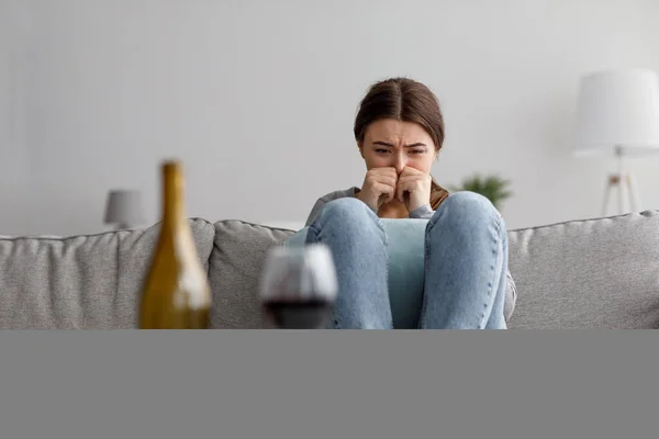 Sorgligt gråtande förtvivlad europeisk ung dam som lider av stress, sorg och svårigheter med flaska och glas vin — Stockfoto