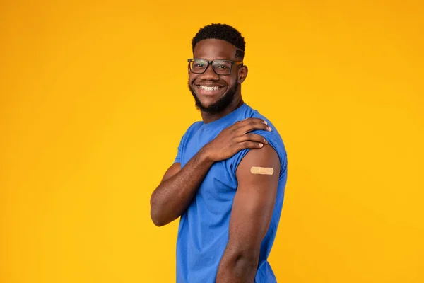 Εμβολιασμένος μαύρος τύπος που δείχνει το χέρι μετά τον εμβολιασμό Covid-19, κίτρινο φόντο — Φωτογραφία Αρχείου