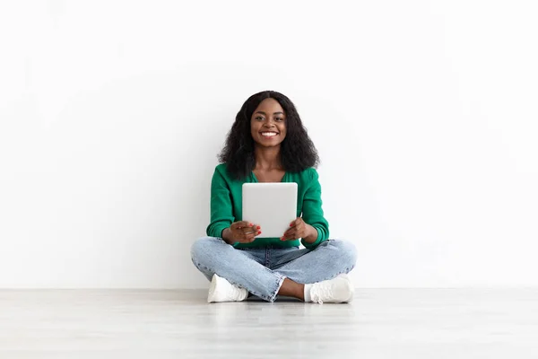 Mujer negra sonriente usando tableta digital, fondo blanco — Foto de Stock