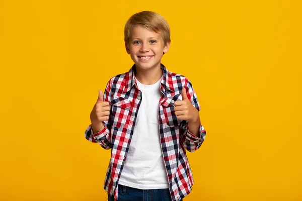 Χαρούμενος έφηβος μαθητής αγόρι δείχνουν τους αντίχειρες επάνω πινακίδα συνιστά κάτι για το σχολείο — Φωτογραφία Αρχείου