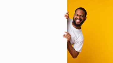 Stüdyoda boş beyaz reklam panolarına bakan siyah bir adam.