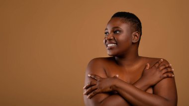 Güzel ve iri yapılı Afrikalı Amerikalı kadın kendini kucaklıyor.