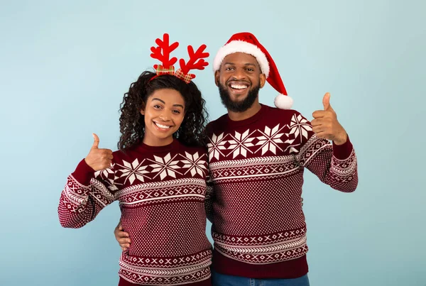Веселого Різдва і щасливого Нового Року. Захоплена парою афроамериканців в однакових светрах, показуючи пальцями вгору. — стокове фото