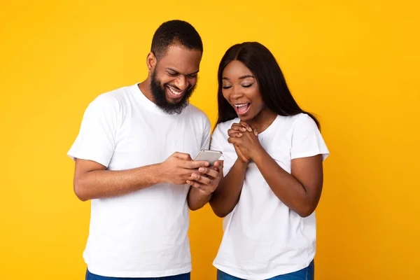 Africano casal americano usando smartphones, amarelo estúdio parede — Fotografia de Stock