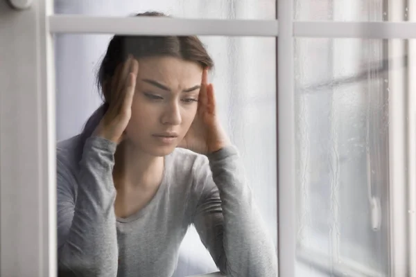 Molestar a las mujeres que sufren de problemas de salud, depresión y dolor de cabeza, cerca de la ventana con gotas —  Fotos de Stock