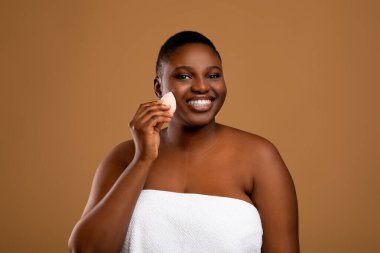 Makyaj fırçası olan güzel siyah tombul kadın.