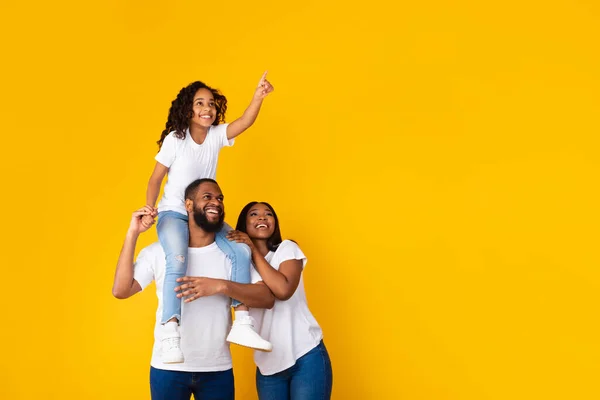 Usmívající se černá rodina ukazuje stranou na kopírovací prostor ve studiu — Stock fotografie