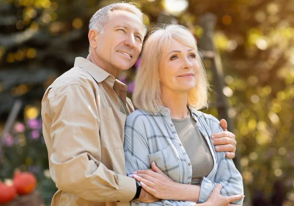 Älskade äldre makar som njuter av de senaste varma höstdagarna, umgås utomhus och tittar bort — Stockfoto