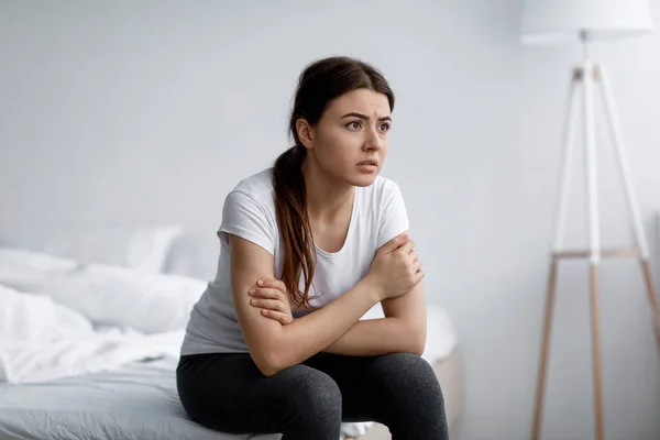 Sorglig ångest ung attraktiv kaukasiska kvinna lider av psykiska problem, stress och sömnlöshet sitter på sängen — Stockfoto