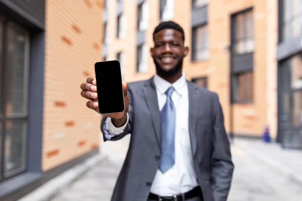 Αφροαμερικανός επιχειρηματίας δείχνει smartphone με άδεια οθόνη, συνιστώντας νέα εφαρμογή για κινητά ή ιστοσελίδα — Φωτογραφία Αρχείου