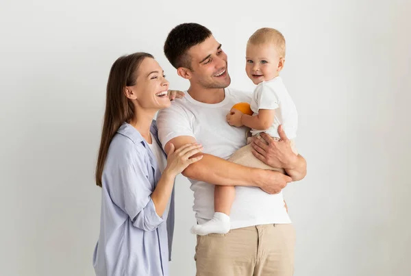 Familia feliz de tres con lindo bebé posando sobre fondo blanco — Foto de Stock