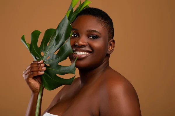 Hermosa mujer negra de tamaño grande sosteniendo hoja de monstera —  Fotos de Stock