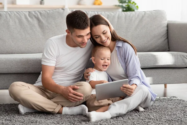 Parents heureux et leur bébé mignon en utilisant la tablette numérique à la maison — Photo