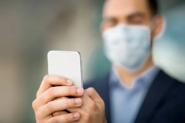 Modern smartphone in unrecognizable businessman hands, man wearing face mask — Stock Photo, Image