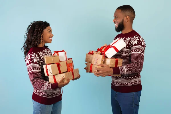 Amantes cônjuges afro-americanos segurando um monte de presentes de xmas e troca de presentes, vestindo camisolas de Natal — Fotografia de Stock