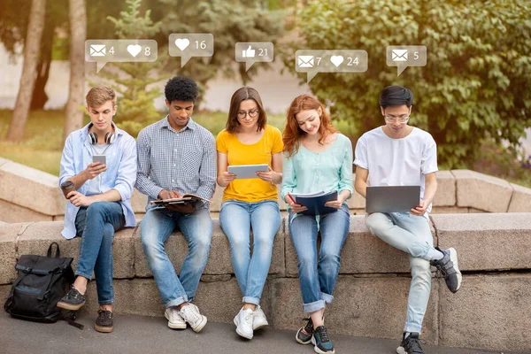 Leende upptagen olika studenter med enheter, surfa och chatta på rast, kontrollera sociala nätverk och online-appar — Stockfoto